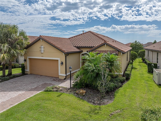 view of front of home with a garage, a tiled roof, decorative driveway, a front lawn, and stucco siding