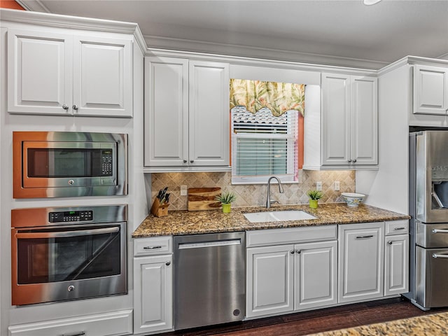 kitchen featuring appliances with stainless steel finishes, backsplash, sink, and white cabinets