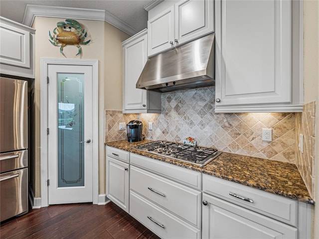 kitchen with dark stone countertops, crown molding, white cabinetry, dark wood-type flooring, and appliances with stainless steel finishes