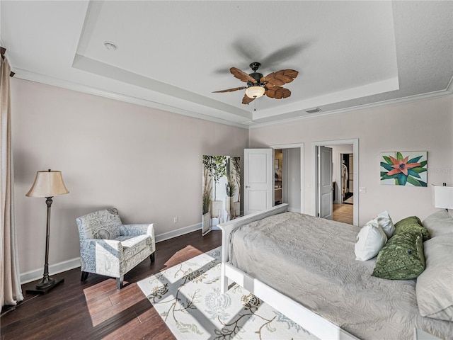 bedroom with dark wood-type flooring, a tray ceiling, ornamental molding, and ceiling fan