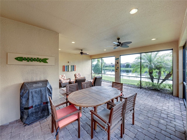 interior space with a water view, ceiling fan, and a healthy amount of sunlight