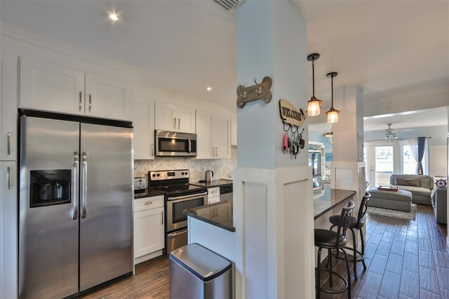 kitchen with backsplash, appliances with stainless steel finishes, dark hardwood / wood-style floors, ceiling fan, and white cabinets