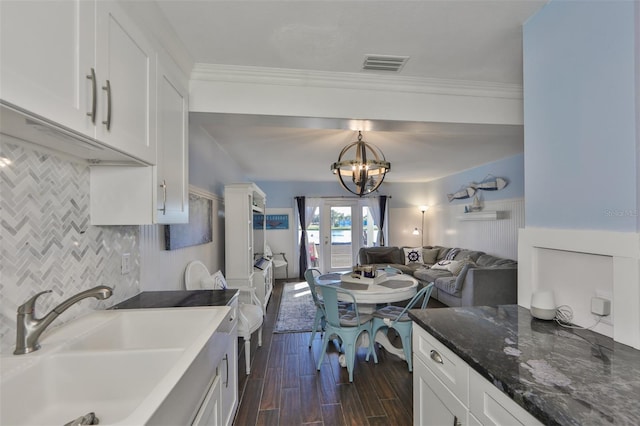 kitchen with decorative backsplash, dark stone counters, a chandelier, white cabinetry, and sink