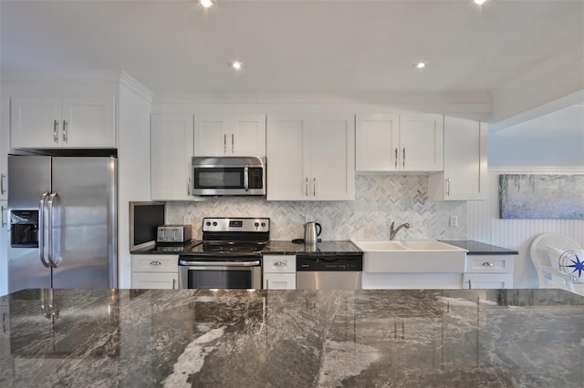 kitchen with dark stone countertops, white cabinetry, decorative backsplash, and stainless steel appliances