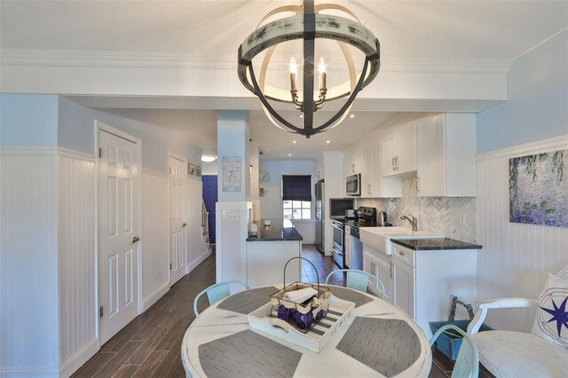 dining area featuring sink, dark wood-type flooring, a chandelier, and ornamental molding