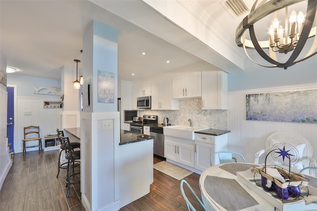 kitchen with backsplash, dark wood-type flooring, a chandelier, white cabinetry, and appliances with stainless steel finishes