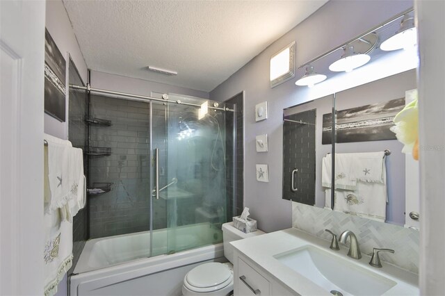 full bathroom featuring tasteful backsplash, a textured ceiling, vanity, combined bath / shower with glass door, and toilet