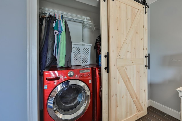 clothes washing area featuring washer and dryer, a barn door, and dark hardwood / wood-style flooring