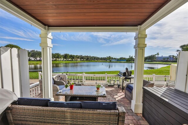 wooden terrace with an outdoor living space, a patio area, and a water view