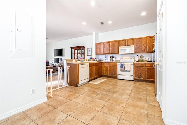 kitchen with light tile patterned flooring, kitchen peninsula, white appliances, and electric panel