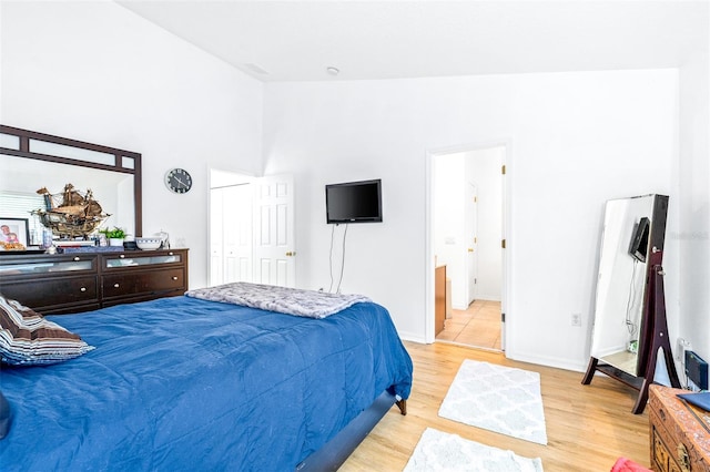 bedroom featuring light wood-type flooring, vaulted ceiling, a closet, and ensuite bathroom