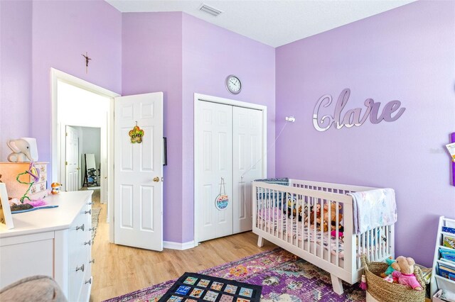 bedroom featuring a closet, light hardwood / wood-style floors, and a crib