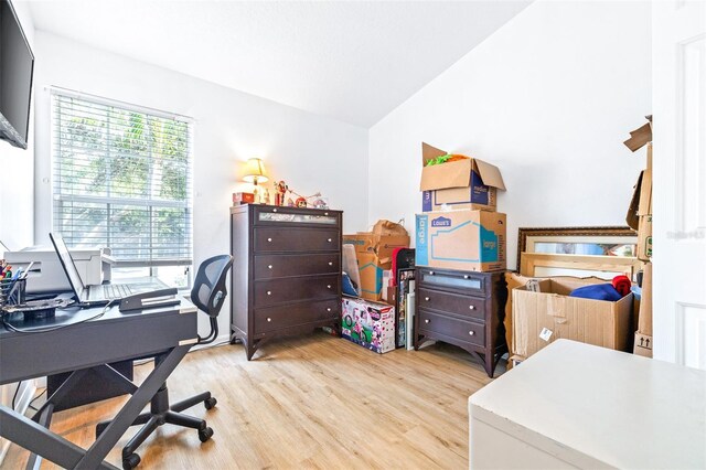 home office with light hardwood / wood-style floors and lofted ceiling