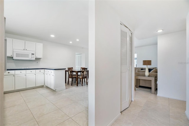 kitchen with light tile patterned floors, kitchen peninsula, and white cabinetry