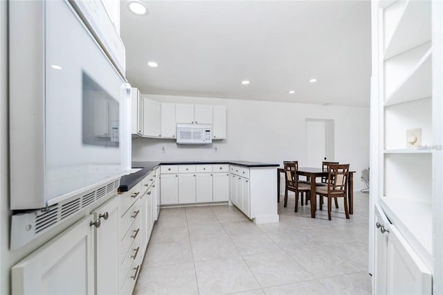 kitchen featuring light tile patterned floors, dark stone countertops, and white cabinets