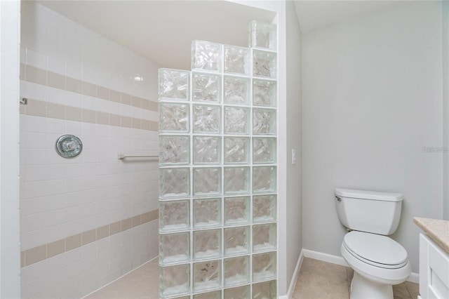 bathroom with tile patterned flooring, toilet, tiled shower, and vanity