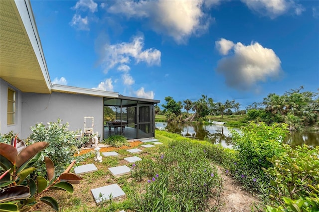 view of yard with a sunroom and a water view