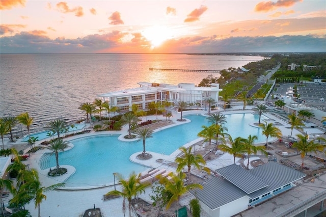 pool at dusk with a patio area and a water view