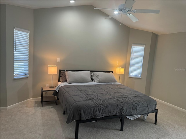 bedroom featuring light colored carpet, vaulted ceiling, multiple windows, and ceiling fan