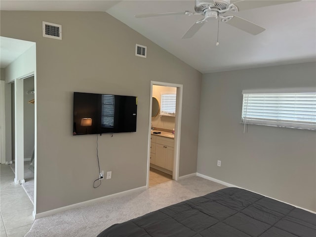 unfurnished bedroom with ceiling fan, vaulted ceiling, connected bathroom, and light tile patterned flooring