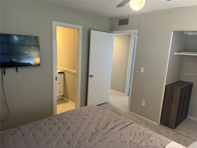 bedroom featuring ceiling fan, light carpet, a closet, and a walk in closet