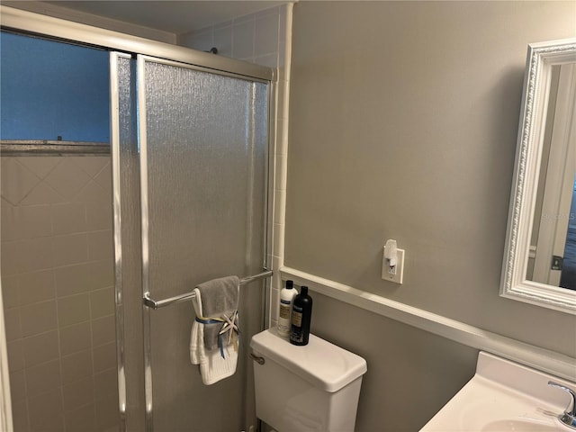 bathroom featuring sink, a shower with shower door, and toilet