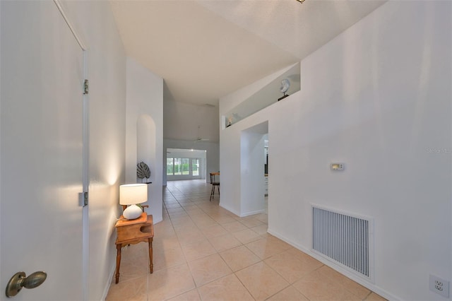 corridor featuring lofted ceiling and light tile patterned floors