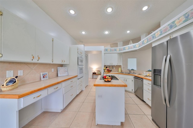 902 Mcdaniel St Unit 1, Sun City Center, FL 33573 - kitchen with appliances with stainless steel finishes, a sink, decorative backsplash, white cabinets, and a textured ceiling