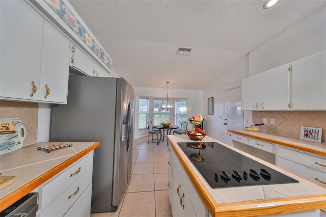 kitchen with appliances with stainless steel finishes, lofted ceiling, white cabinetry, and hanging light fixtures