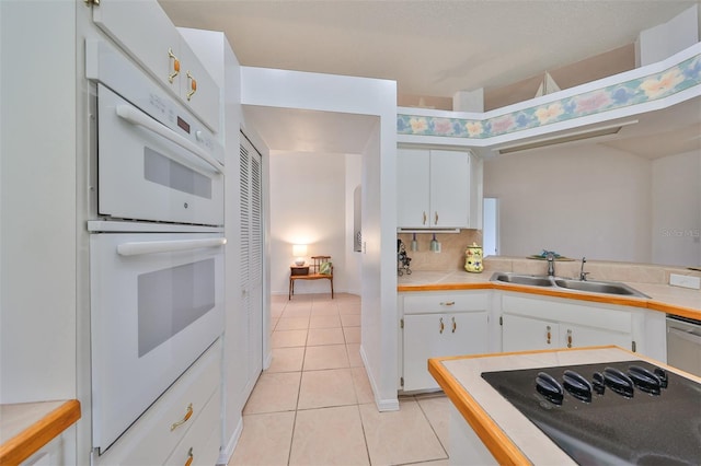 kitchen with white cabinets, sink, light tile patterned floors, and white double oven