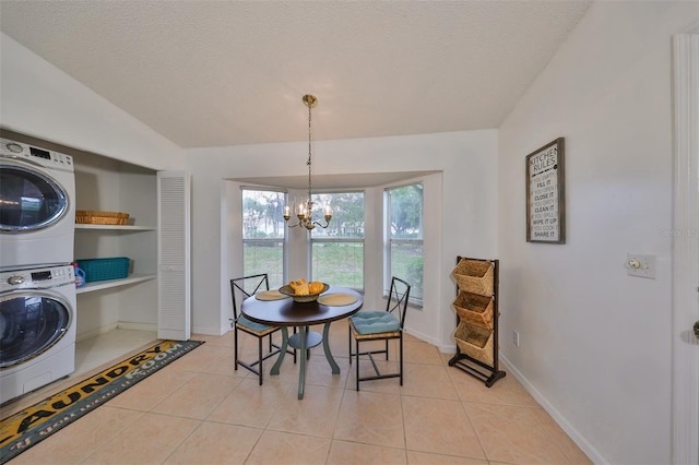 tiled dining space with stacked washer / drying machine, a notable chandelier, and a textured ceiling