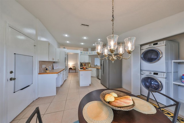 interior space with dishwasher, a center island, white cabinetry, stacked washing maching and dryer, and light tile patterned floors