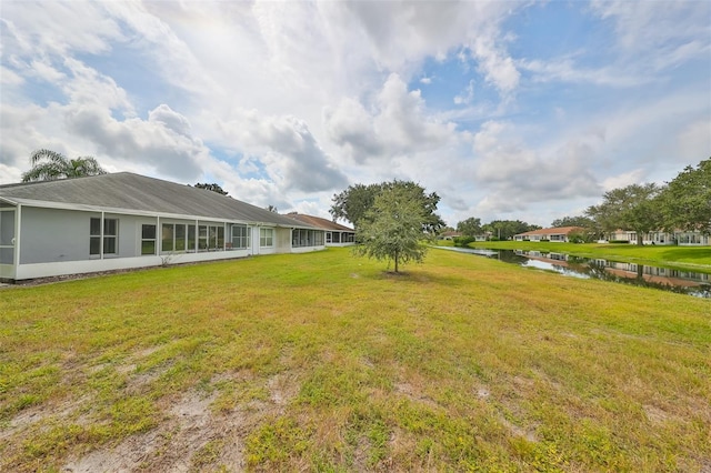 view of yard with a sunroom and a water view