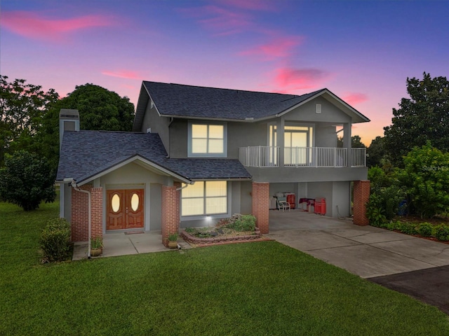 view of front facade featuring a balcony, a garage, and a lawn