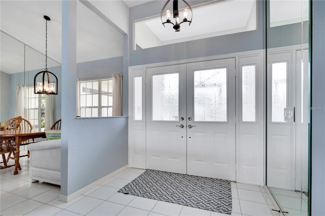 tiled entryway with a healthy amount of sunlight and a chandelier