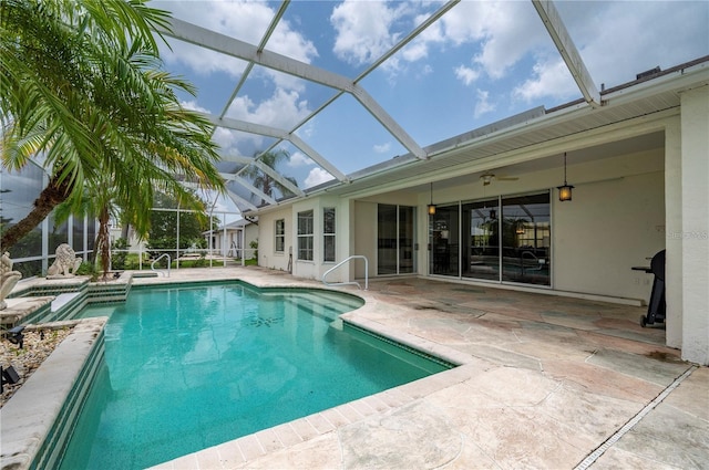 view of pool with glass enclosure, a patio, and ceiling fan