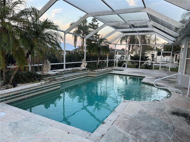 pool at dusk featuring a patio area and a lanai