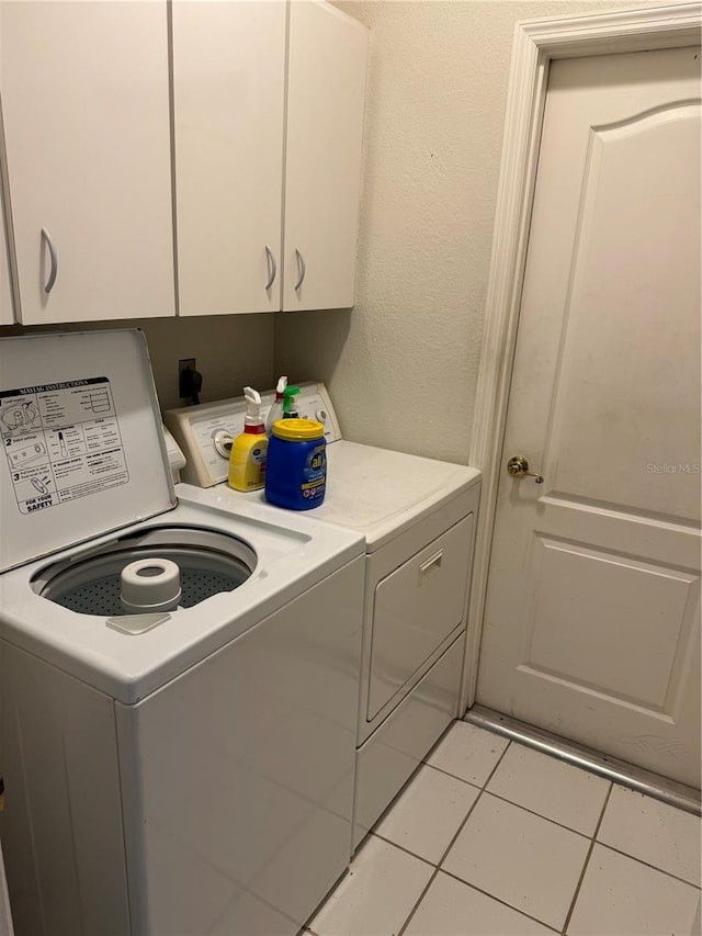 laundry area with light tile patterned floors, separate washer and dryer, and cabinets