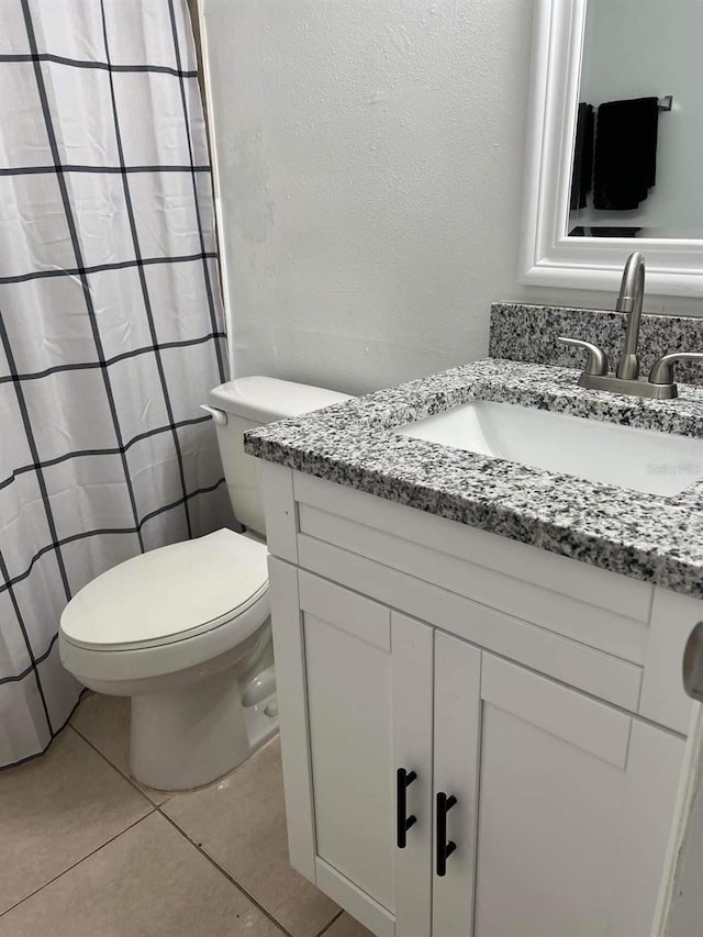 bathroom with toilet, tile patterned flooring, and vanity