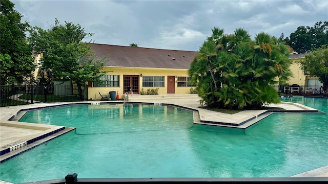 pool with a patio area and fence