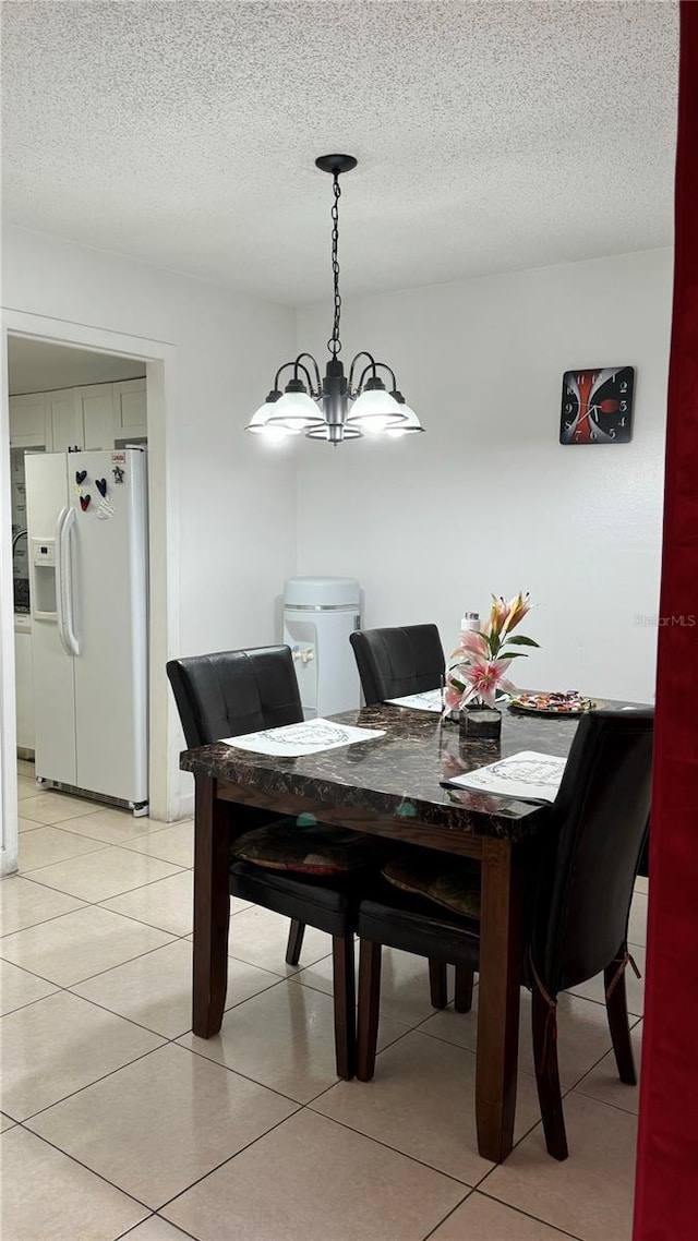 dining space featuring a textured ceiling, light tile patterned floors, and a notable chandelier