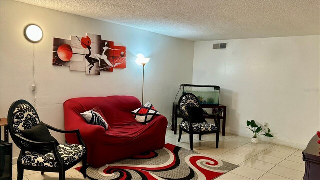 living area featuring visible vents, a textured ceiling, baseboards, and light tile patterned floors