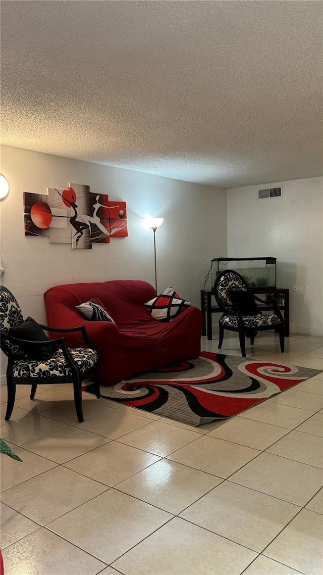 living room with visible vents, a textured ceiling, and light tile patterned floors