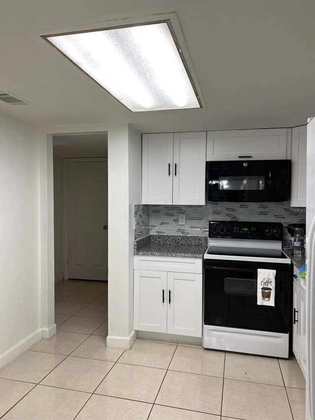 kitchen featuring range with electric cooktop, black microwave, white cabinetry, and light tile patterned floors