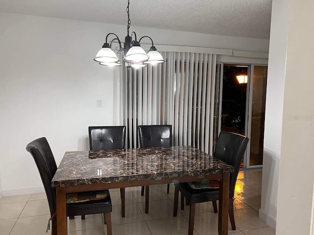 dining area with a textured ceiling, light tile patterned flooring, a notable chandelier, and baseboards