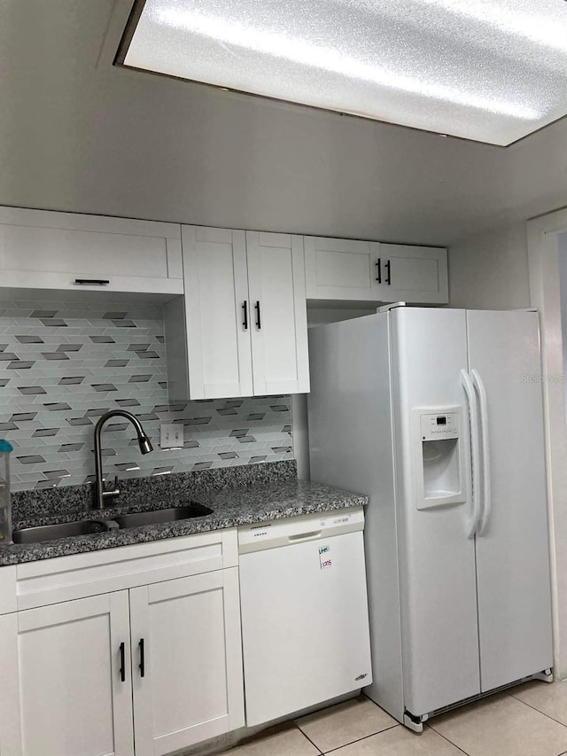 kitchen featuring dark stone counters, white appliances, a sink, and white cabinets