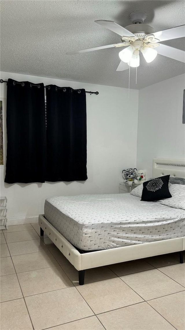 bedroom with light tile patterned floors, ceiling fan, and a textured ceiling