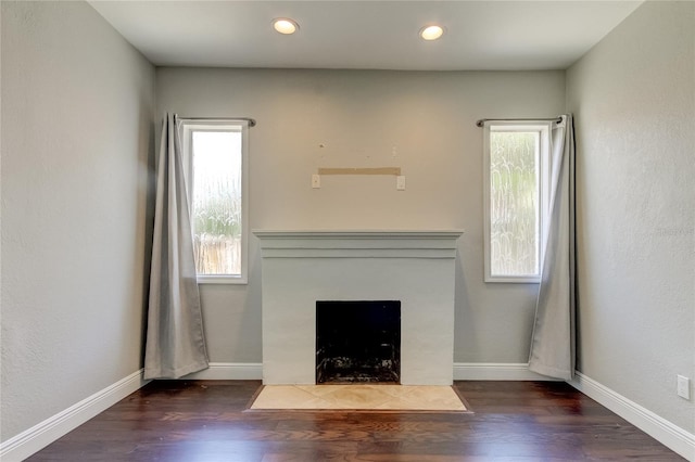 unfurnished living room with a tiled fireplace and dark hardwood / wood-style floors