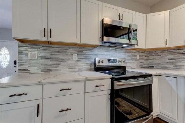 kitchen with appliances with stainless steel finishes, tasteful backsplash, light stone countertops, and white cabinets