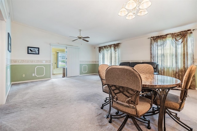 dining space with ceiling fan with notable chandelier, crown molding, and light colored carpet